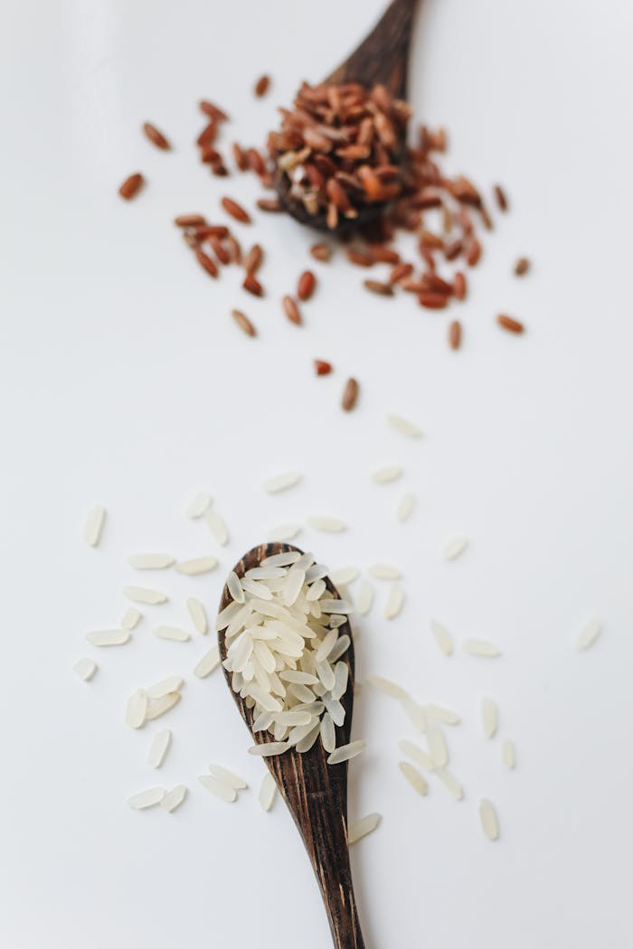 Close-up of brown and white rice grains in wooden spoons, showcasing natural food textures.